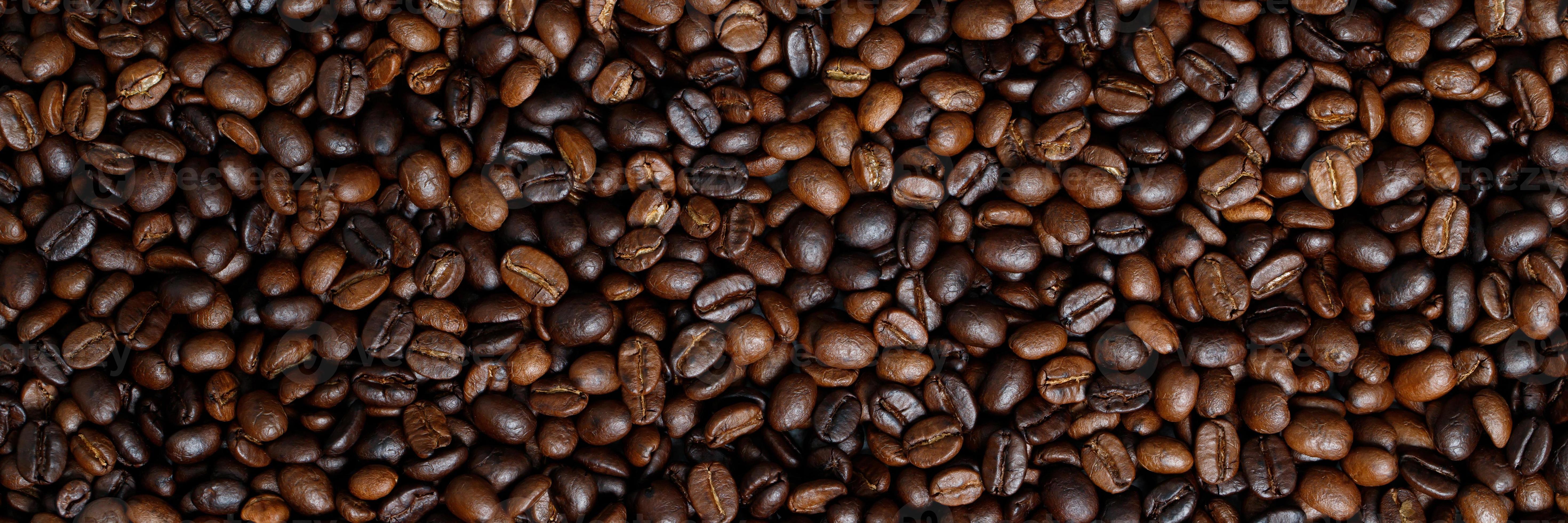 Primer plano de granos de café tostado sobre fondo oscuro, textura del laboratorio de tostado